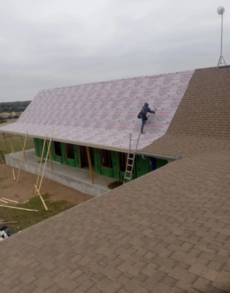 Worker preparing underlayment for a metal roof installation in Bolivar